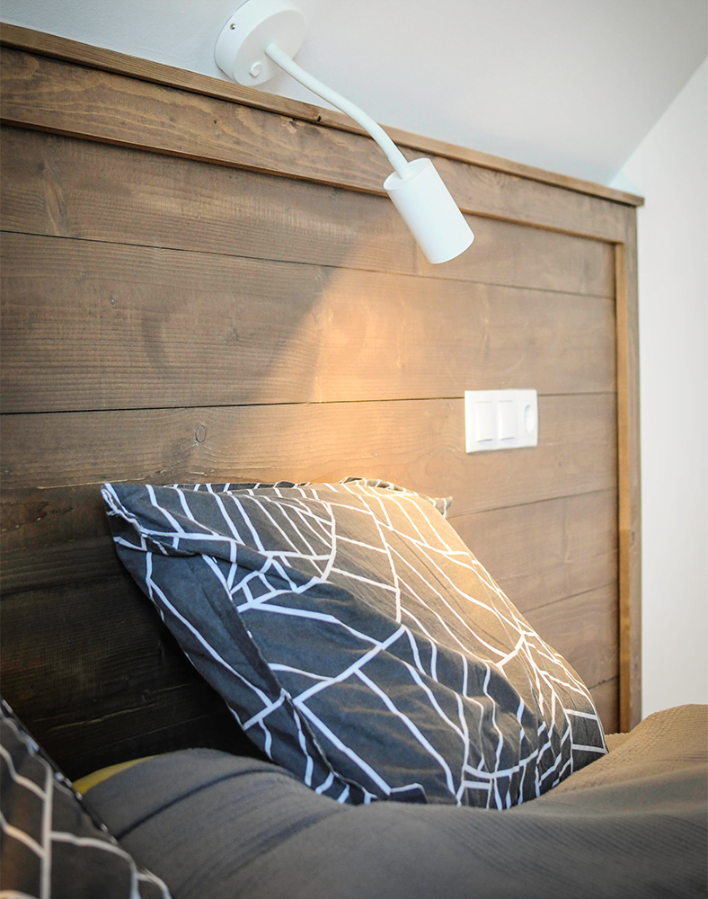 Un pat rustic cu spatar,perna si lampa